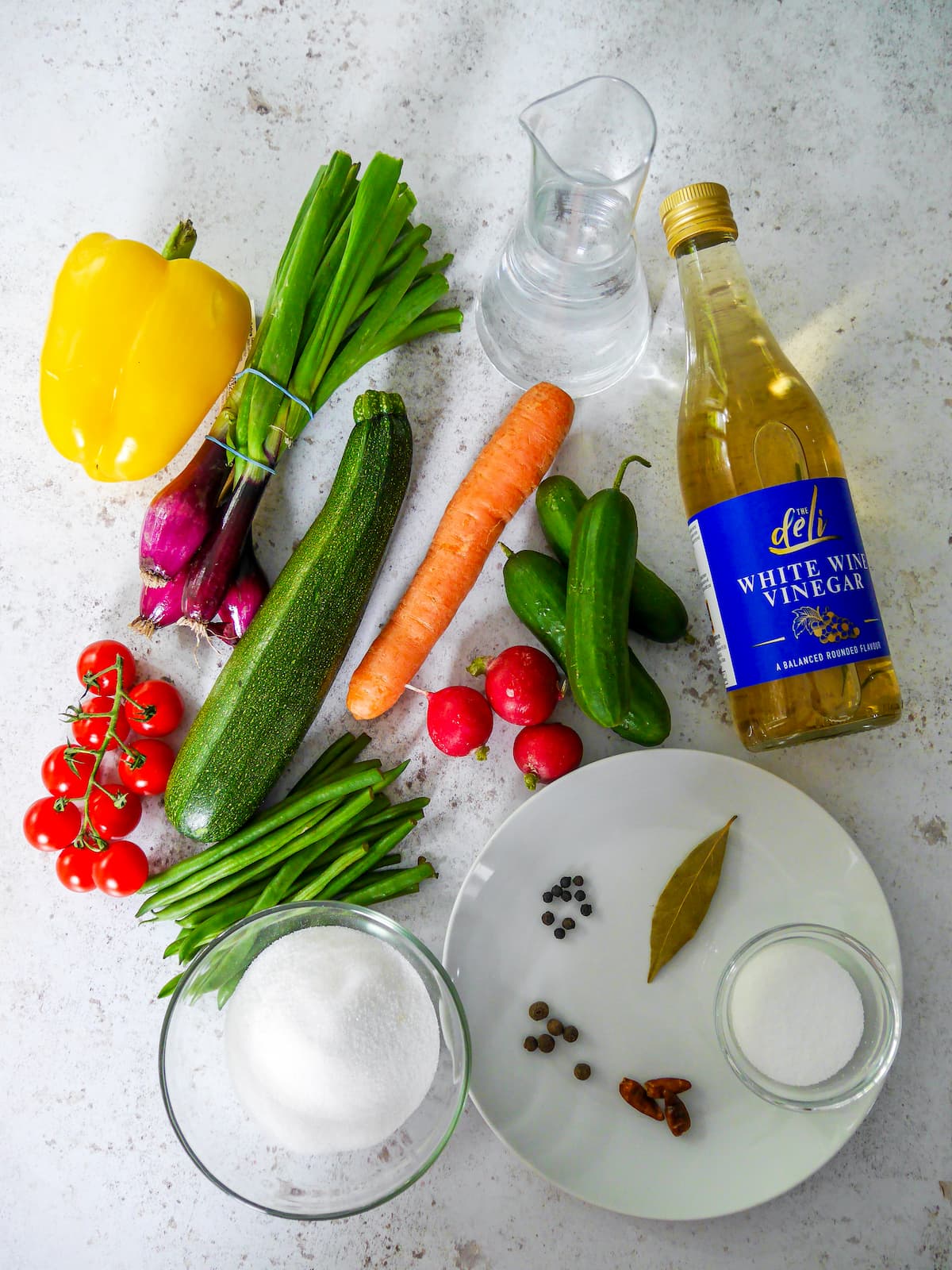 Individual recipe ingredients for making summer vegetable pickles.