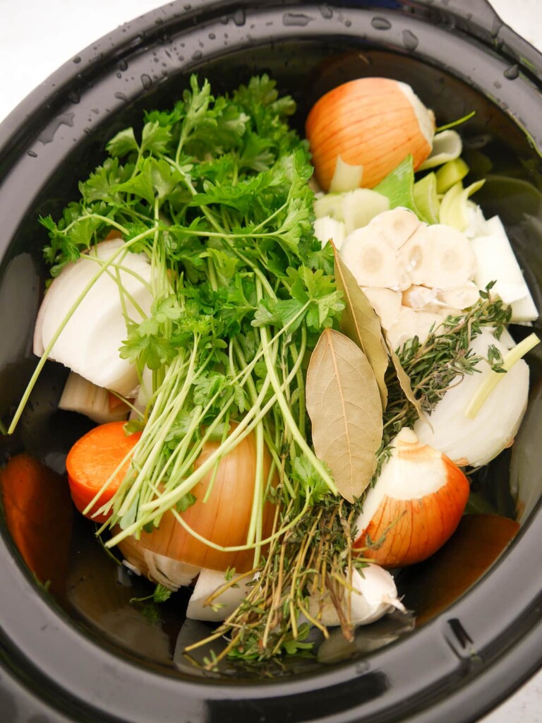 A slow cooked bowl filled with a variety of roughly chopped vegetables and fresh herbs.