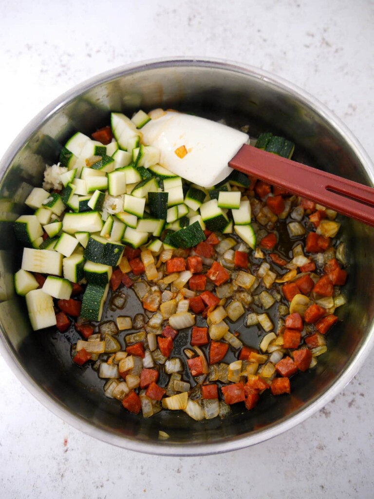 A large frying pan of sauteed chorizo and vegetables.
