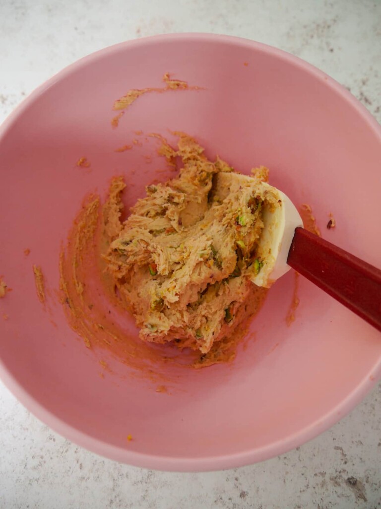 A pink bowl of pistachio and lemon cookie dough.