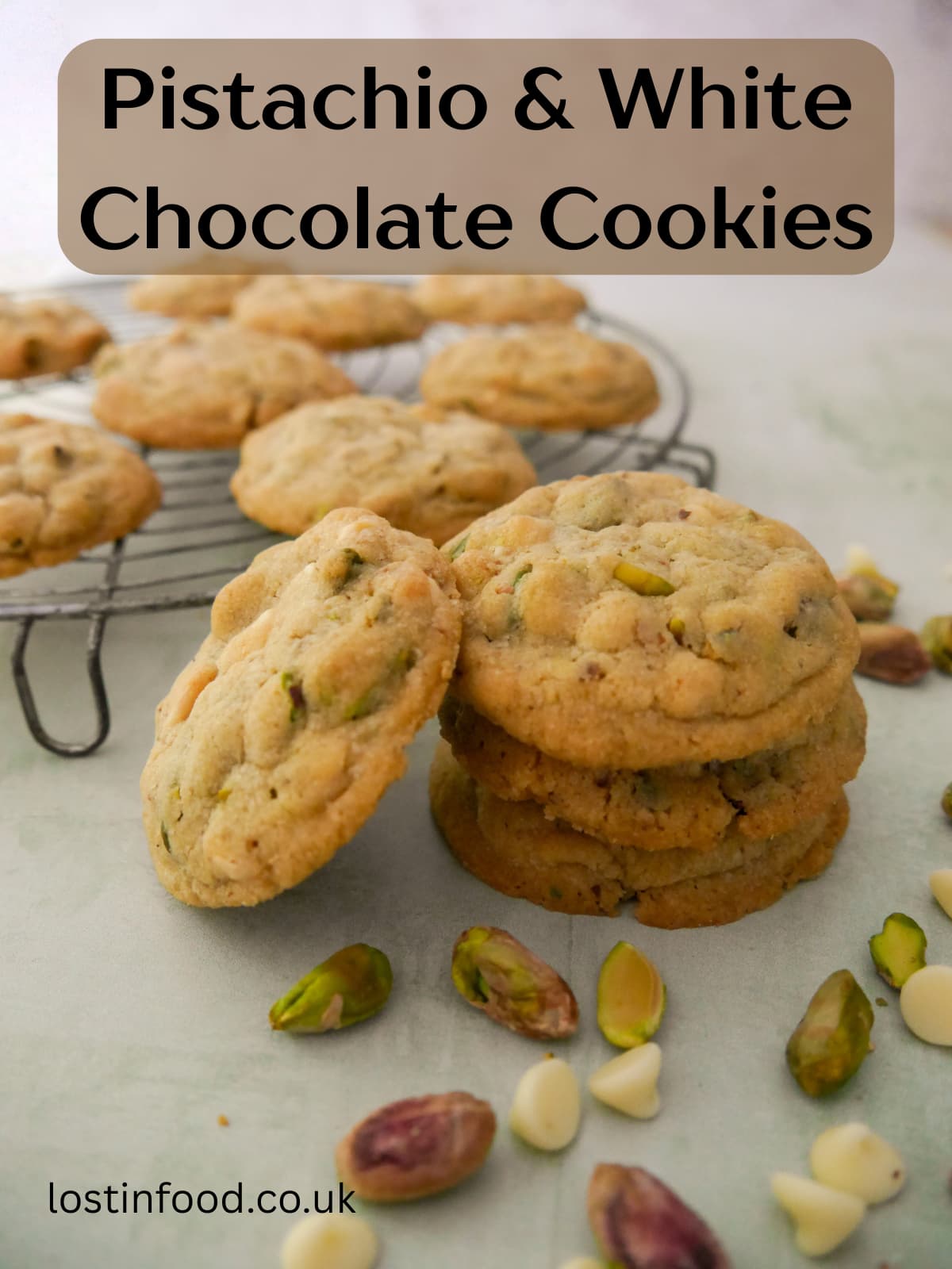 Pinnable image with recipe title and a stack of pistachio white chocolate cookies with a wire rack of cookies set alongside.