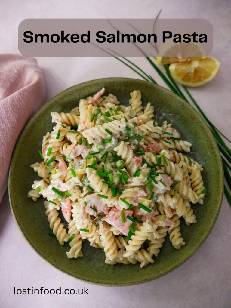 Pinnable image and recipe title with a green bowl filled with smoked salmon pasta garnished with chopped chives with a wedge of lemon and chives set alongside.