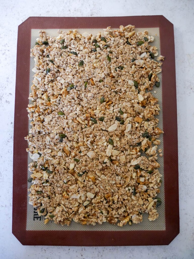 A lined baking sheet covered in granola mixture.