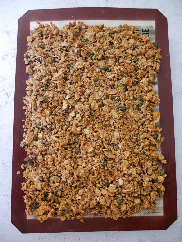 A lined baking sheet of cooked granola.