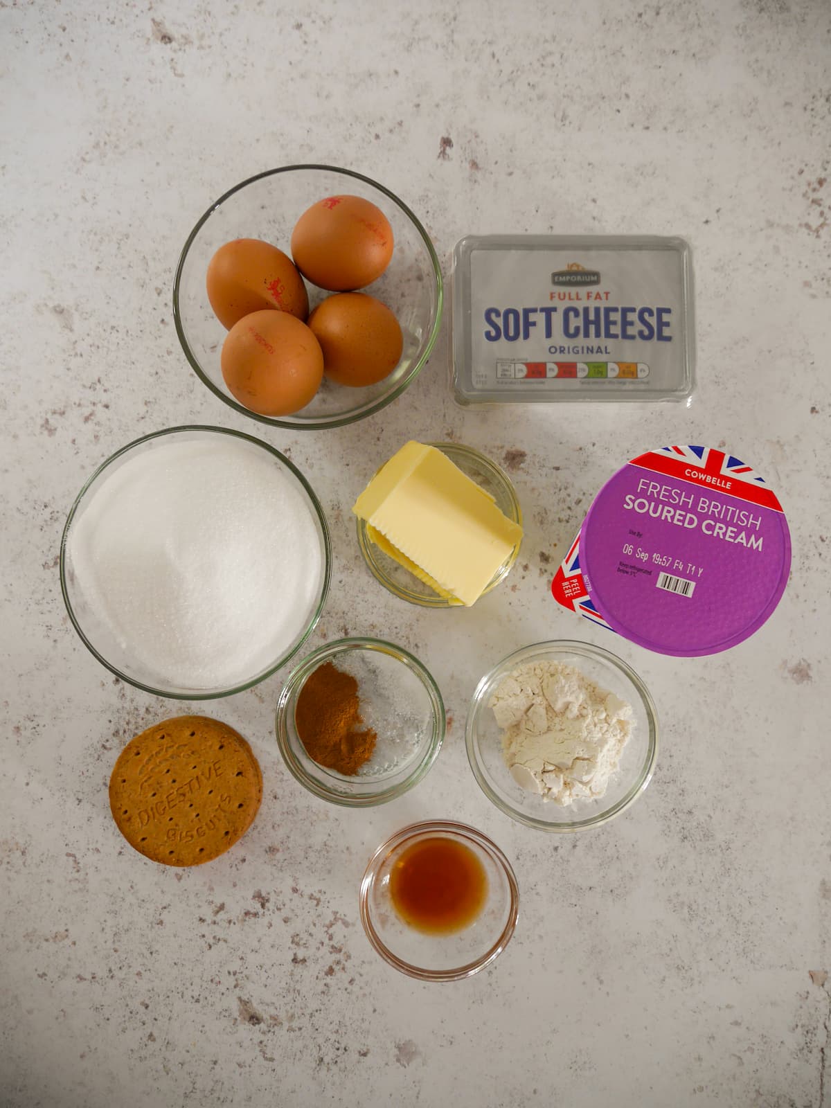 Individual recipe ingredients for making a baked vanilla cheesecake.