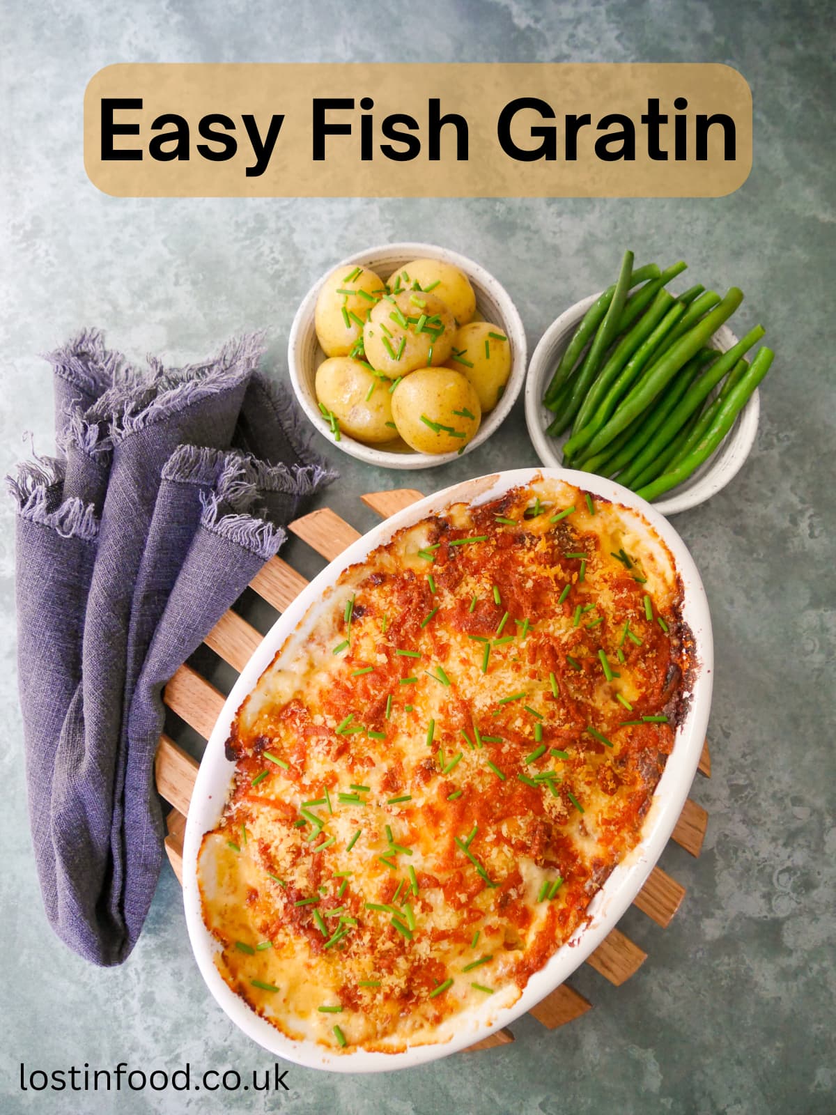 Pinnable image with recipe title and an oven proof dish of fish gratin served with sides of buttered chive new potatoes and green beans.