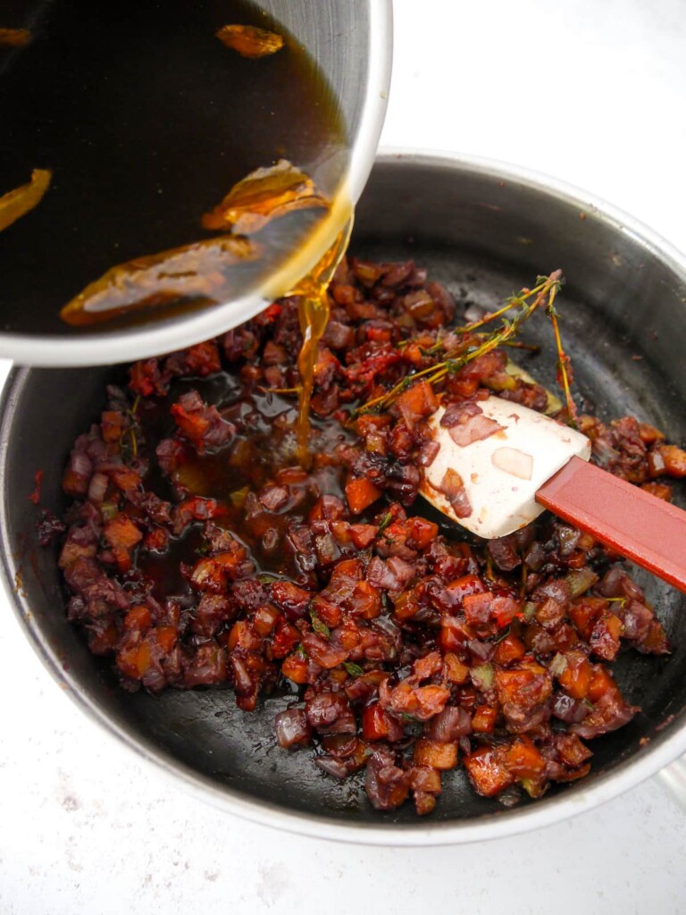 Porcini mushroom broth being added to vegan gravy base vegetatables.