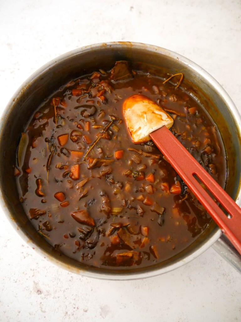 A large skillet filled with cooked and thickened vegan gravy.