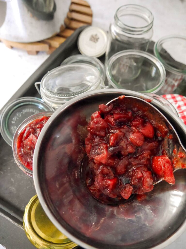 Fruit chutney being spooned into sterilised jars.