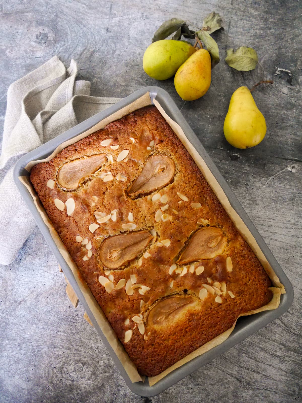 A baking tray filled with a baked pear and almond cake.