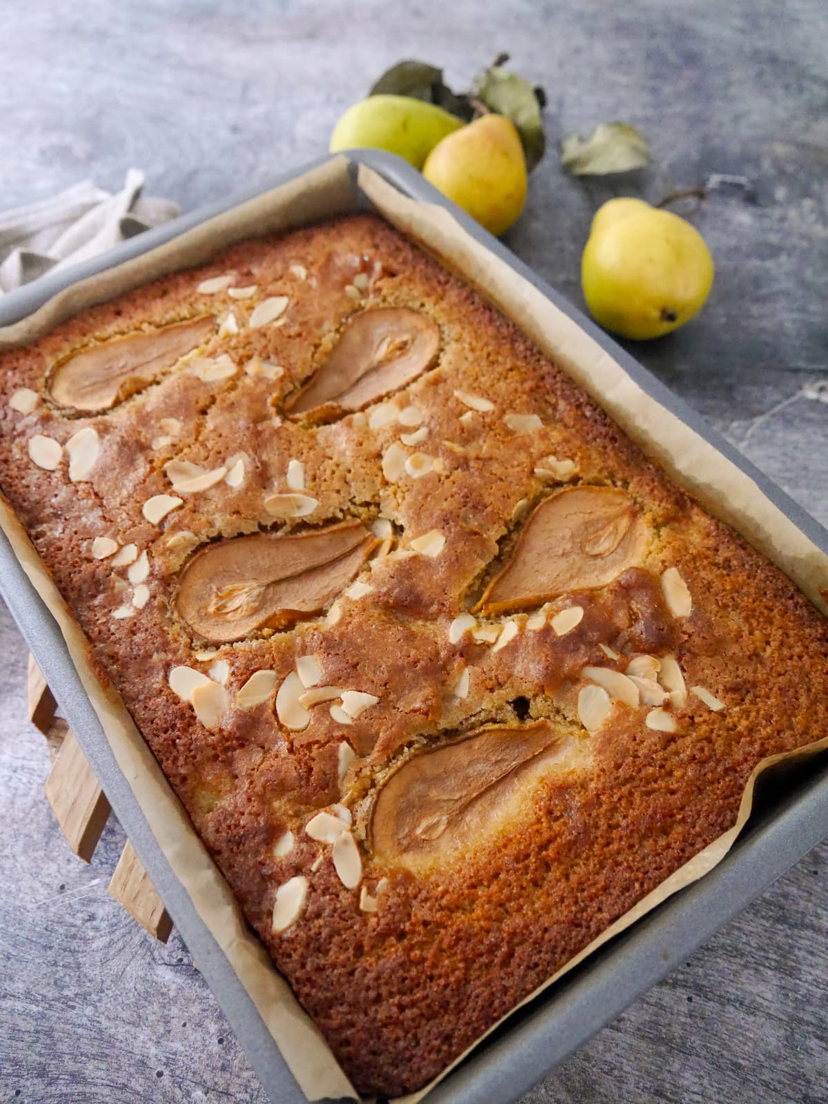 A baking tray filled with a baked pear and almond cake.