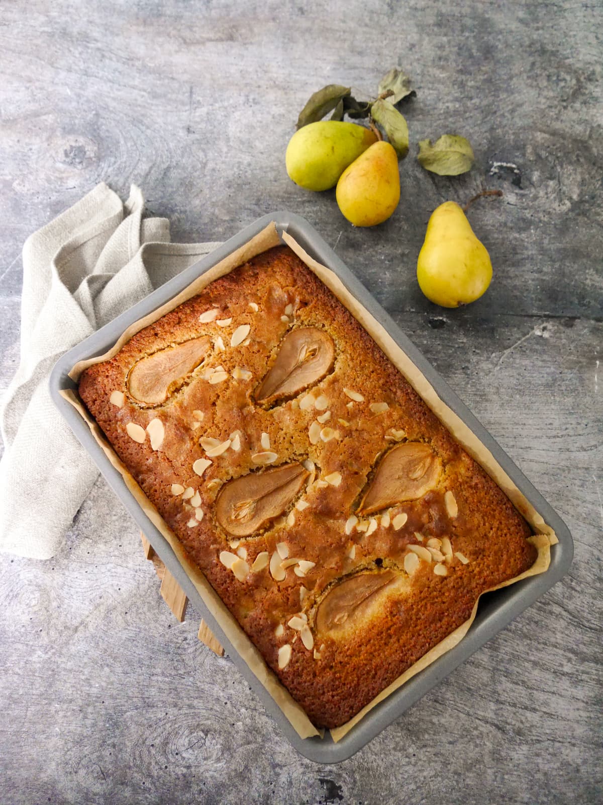 A baking tray filled with a baked pear and almond cake.