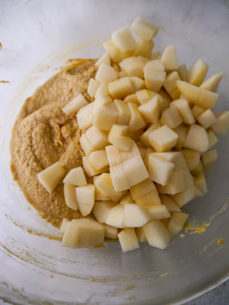 A bowl of cake batter with added chopped pear.