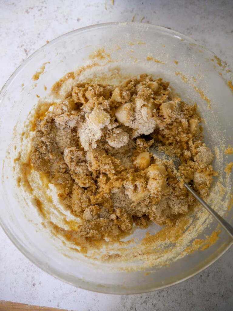 A bowl of cake batter with chopped pear stirred through.