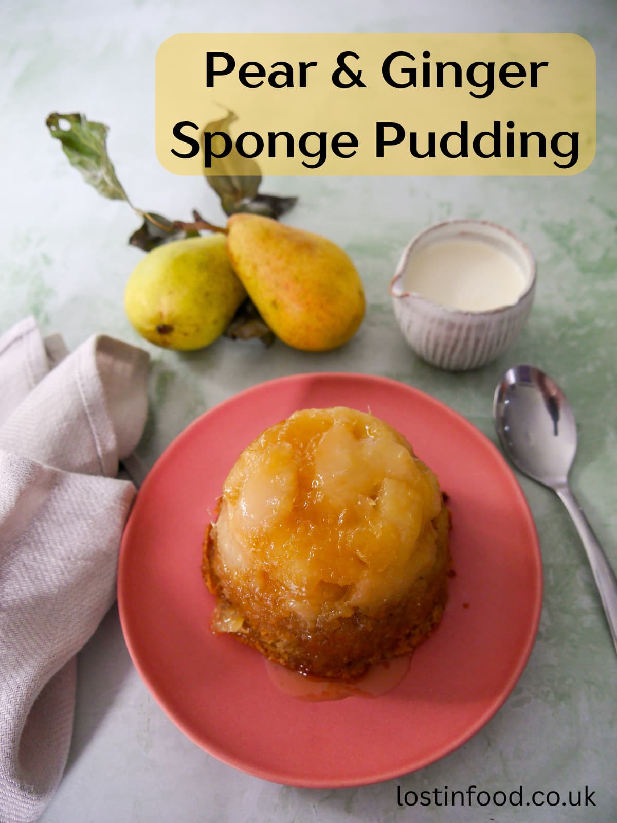 Pinnable image with recipe title and a pink plate topped with and individual pear and ginger sponge pudding with a jug of cream set alongside.