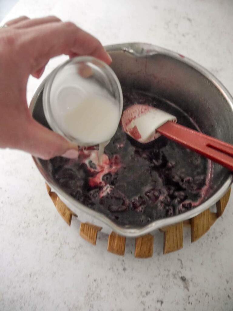Black cherry compote with cornflour and water paste being added.