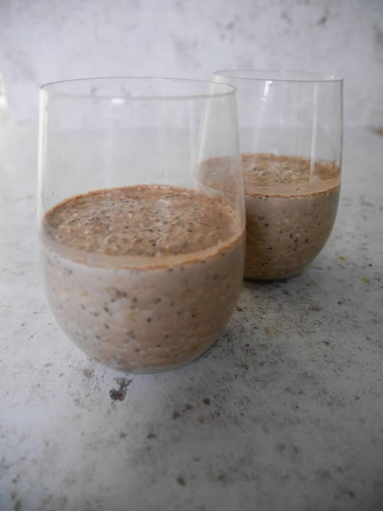 Two glasses half filled with chocolate orange overnight oats.