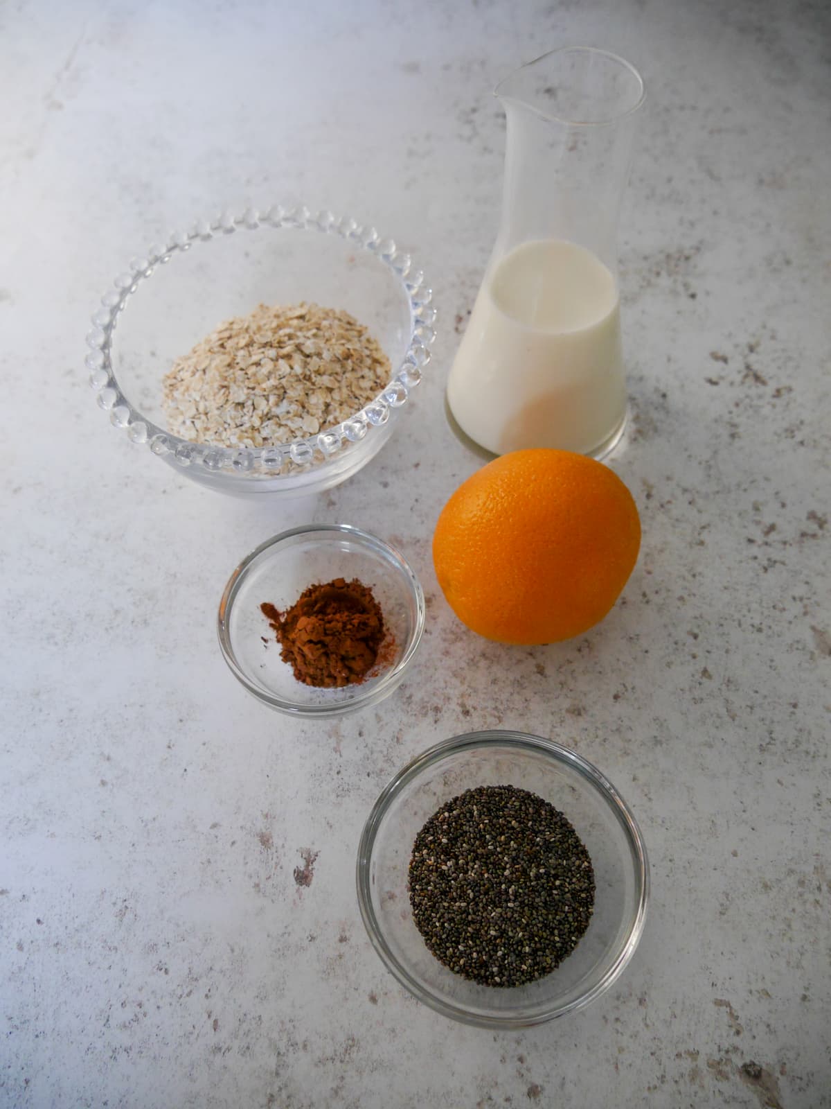 Individual recipe ingredients for making chocolate orange overnight oats.