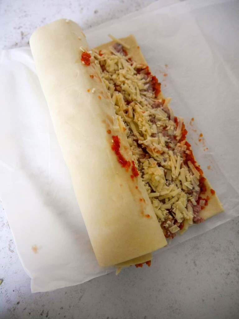 A rolled up sheet of puff pastry filled with chilli jam, sausage meat and grated cheddar cheese.