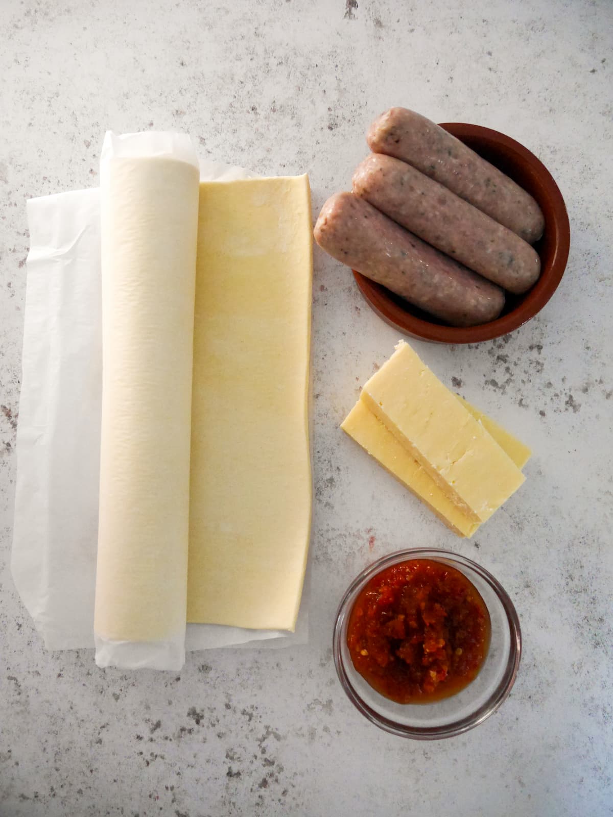 Individual recipe ingredients for making sausage pinwheels with puff pastry.