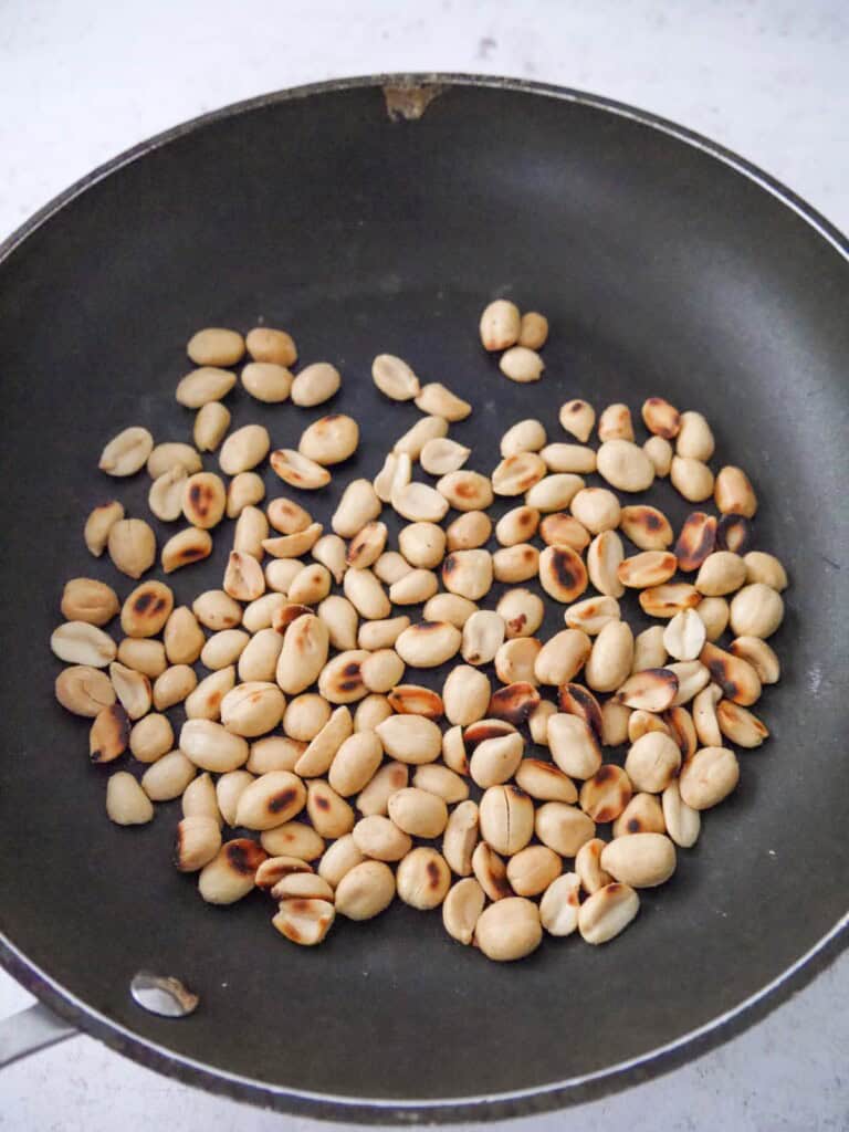 A non stick frying pan with toasted peanuts.