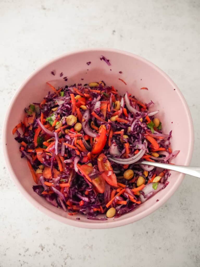 A bowl of peanut and ginger slaw ingredients, mixed thoroughly to combine.