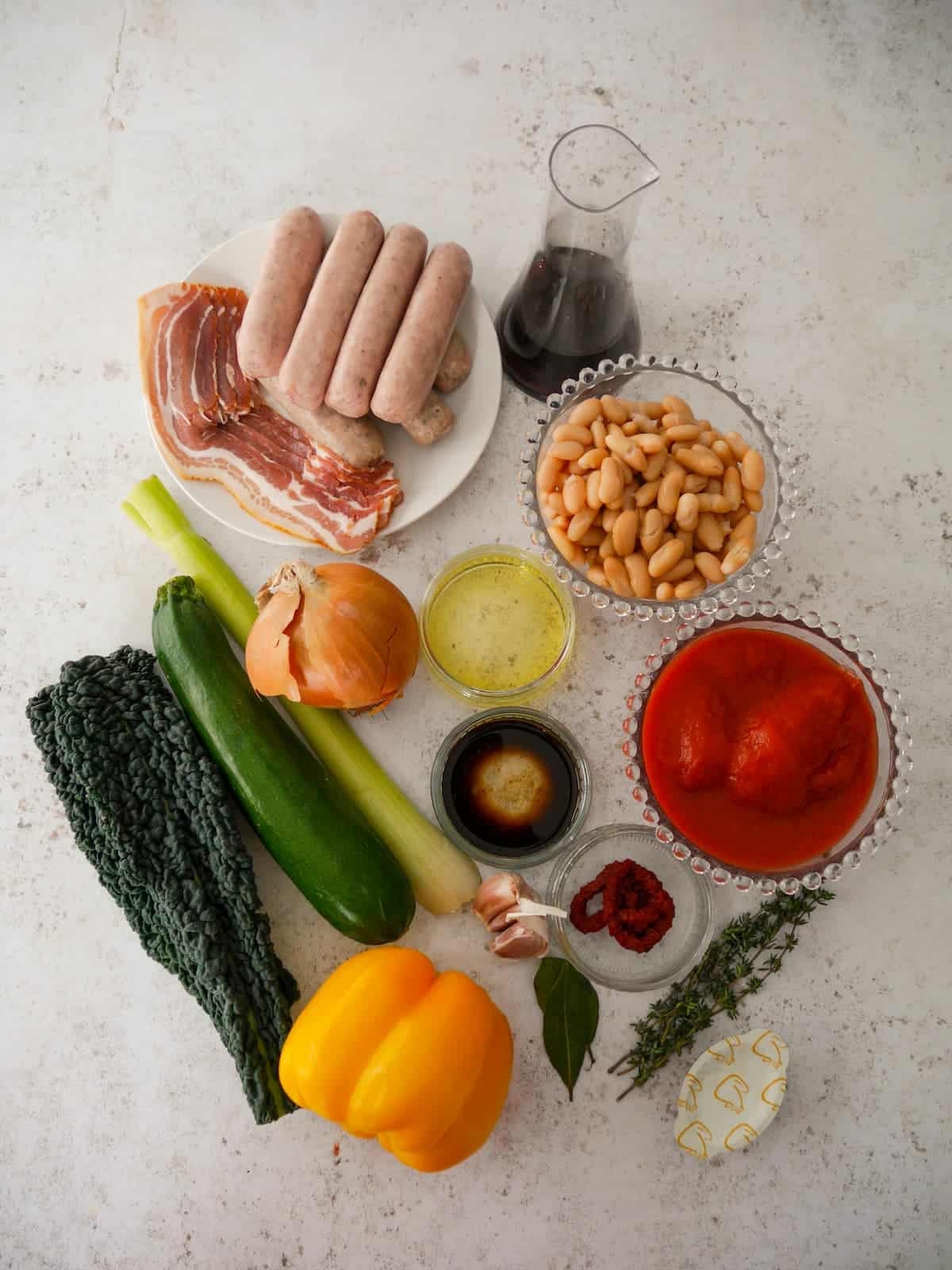 Individual recipe ingredients for making sausage casserole with white beans and kale.