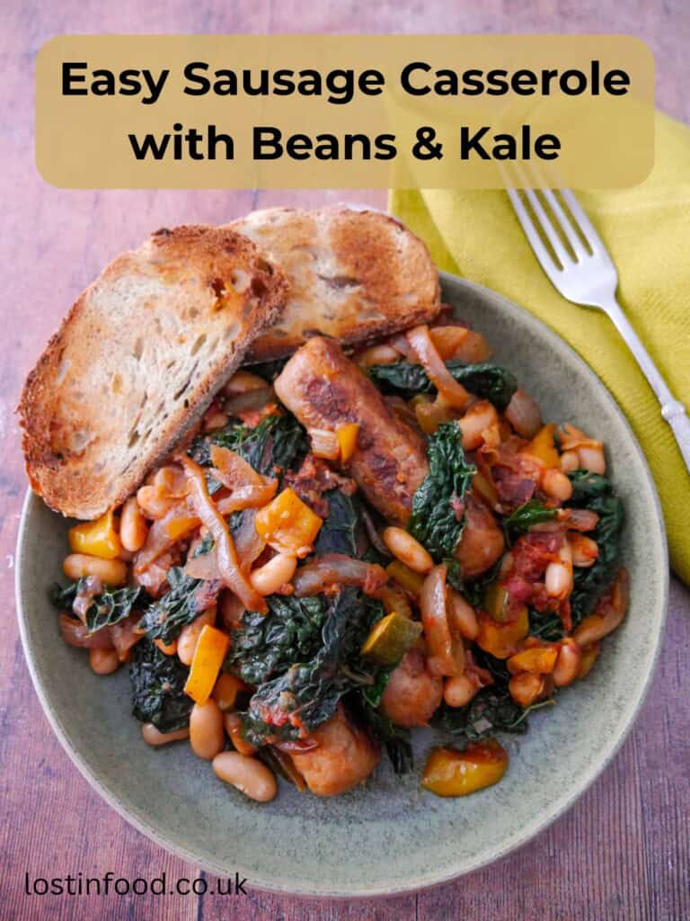 Pinnable image with recipe title and a bowl of sausage casserole with added cannellini beans and cavolo nero kale, served with toasted bread.