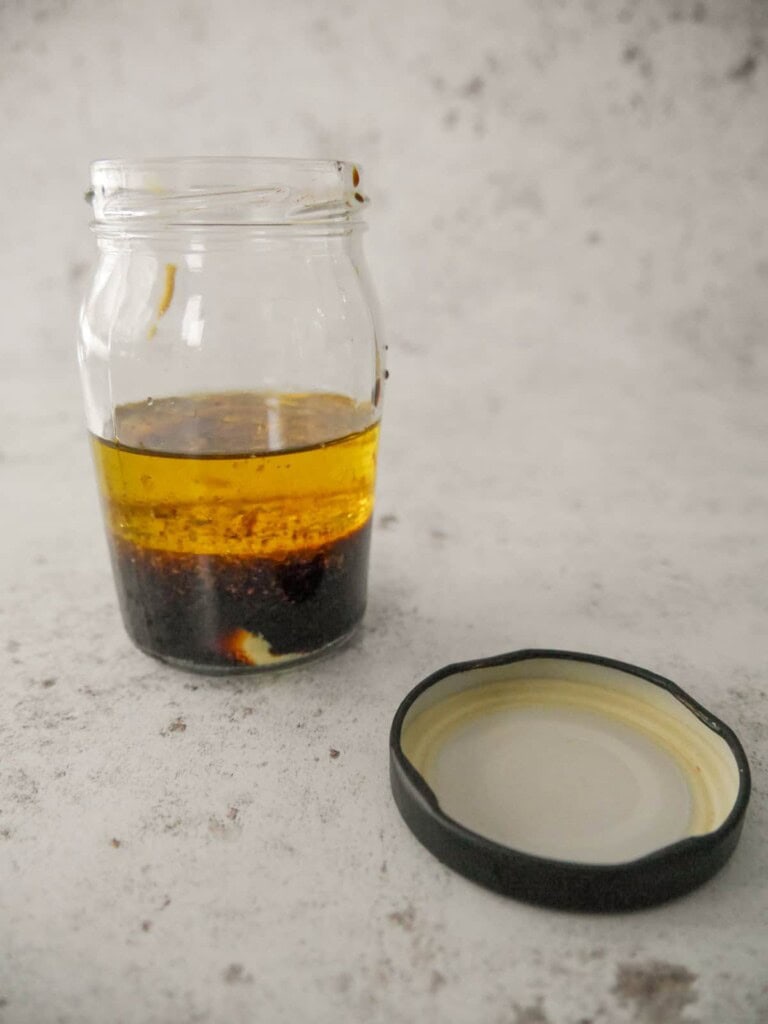 Individual recipe ingredients for making soy and ginger dressing layered up in a jar.