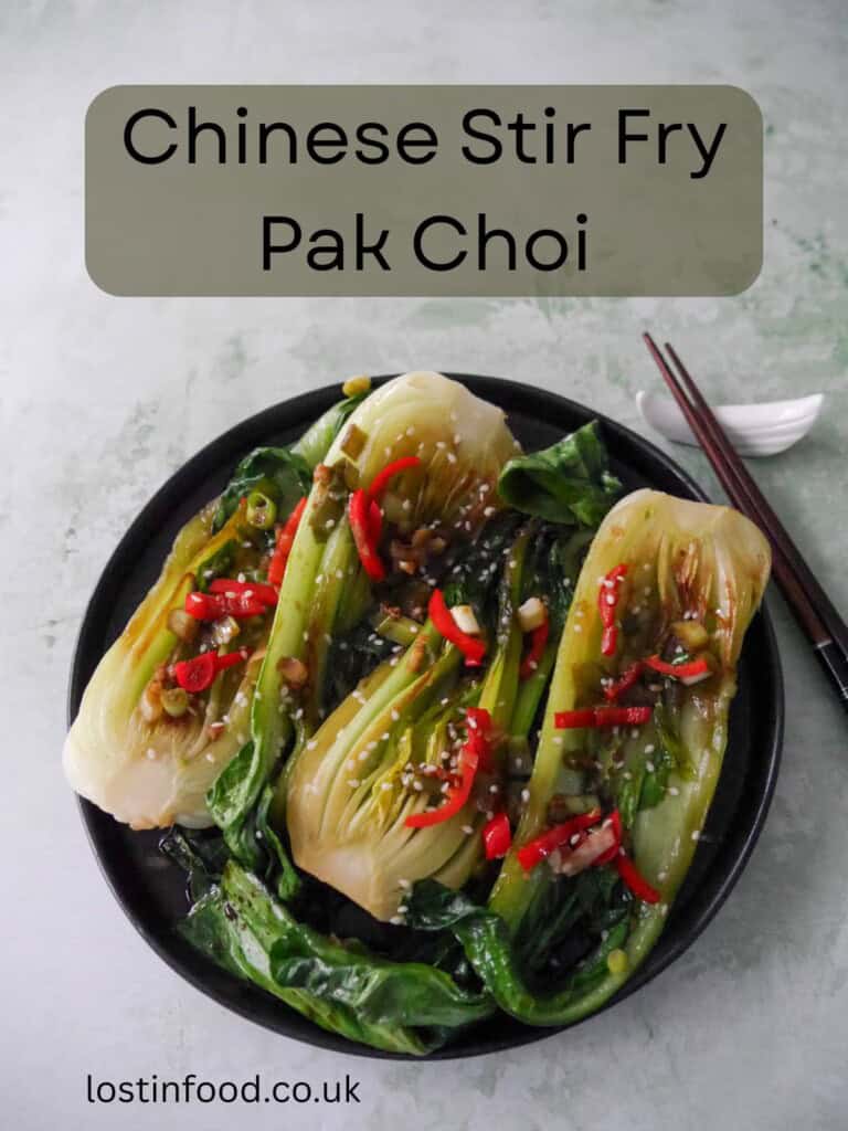 Pinnable image with recipe title and a plate of Chinese stir fry pak choi with garlic, red chillies and spring onion, garnished with sesame seeds.