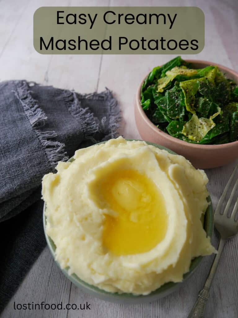 Pinnable image with recipe title and a bowl of creamy mashed potatoes, topped with some butter and a bowl of buttered spring greens set alongside.