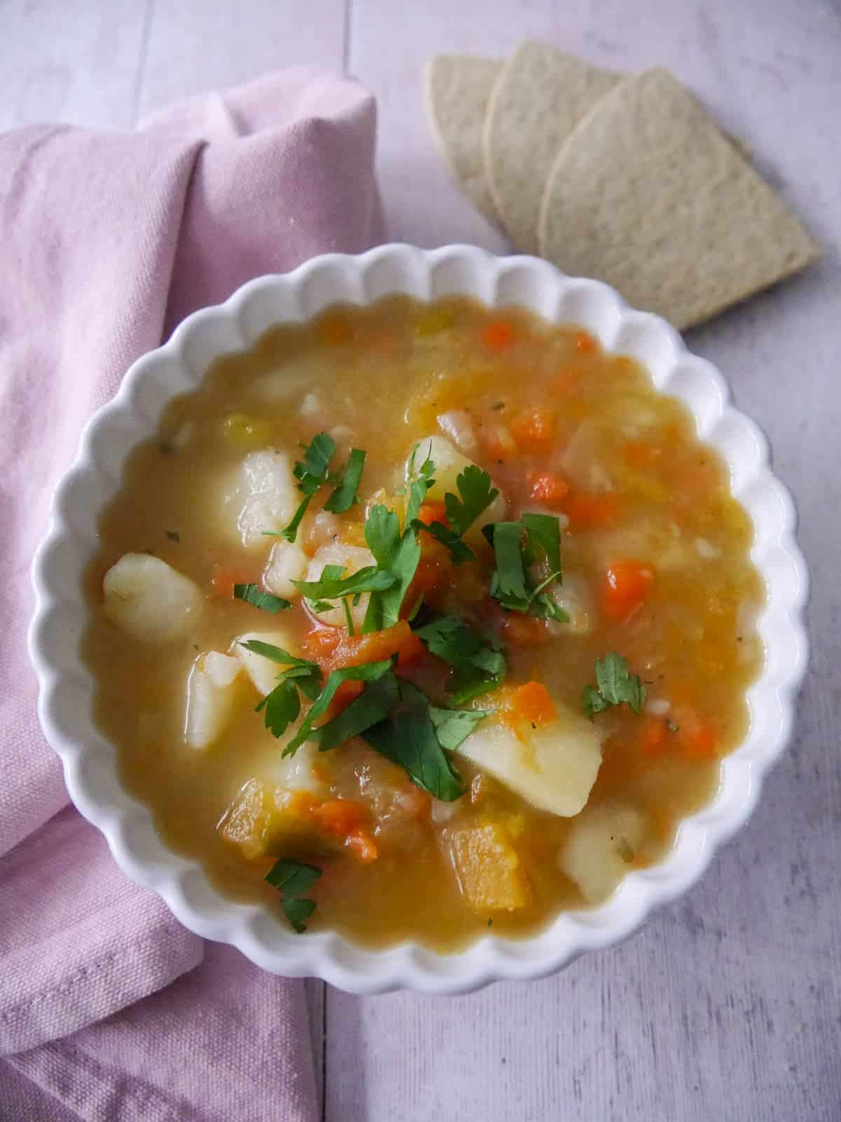 A bowl of potato and vegetable soup with some oatcakes served alongside.