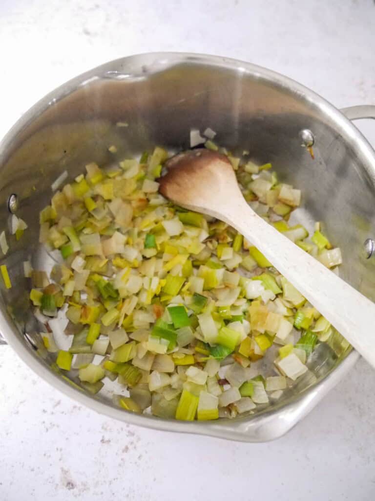 A large pan with sauteed onion and leek.