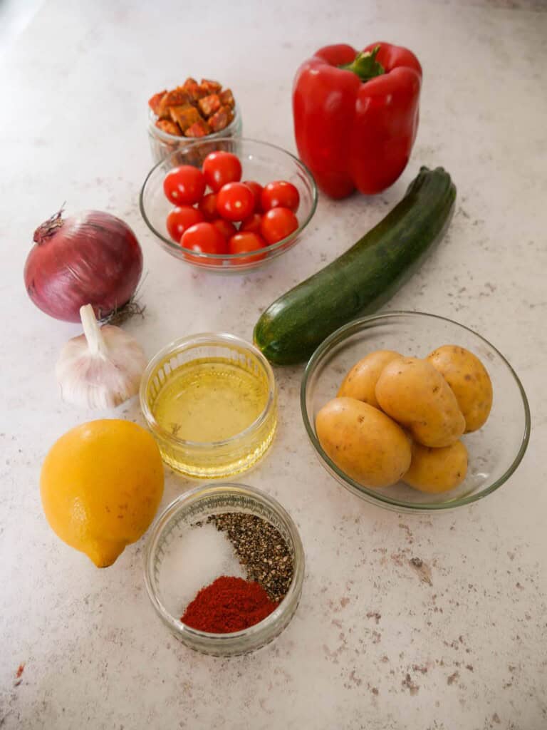 Individual recipe ingredients for making cajun chicken and vegetable traybake.