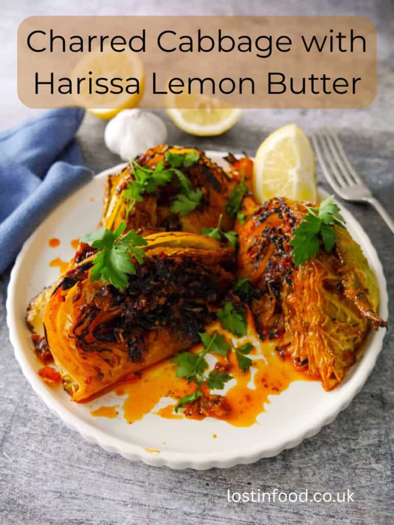 Pinnable image with recipe title and a plate of 3 charred wedges of savoy cabbage cooked in a harissa and lemon butter, garnished with fresh parsley and serve with a wedge of lemon.