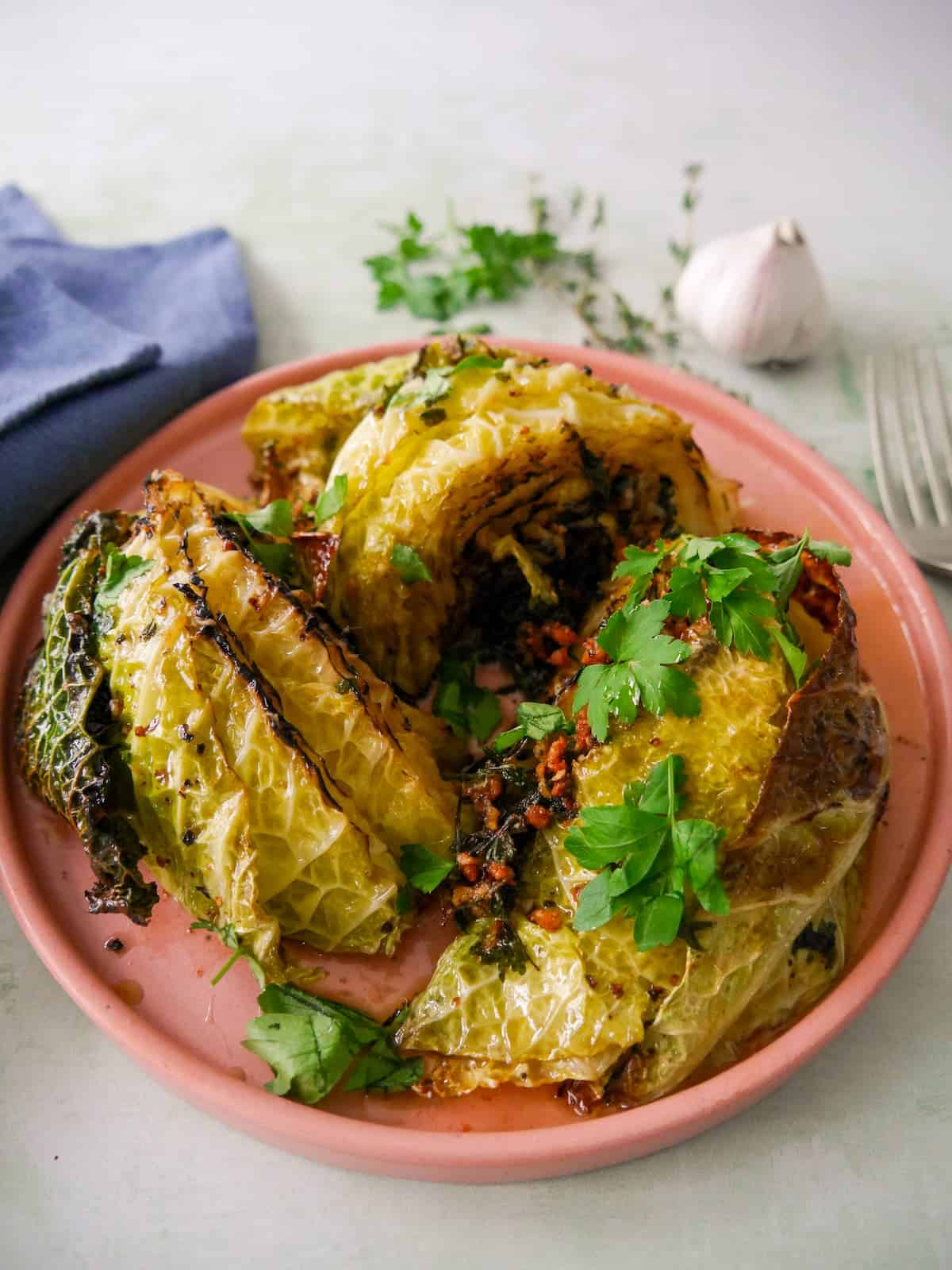 A plate of charred savoy cabbage wedges cooked in a garlic and herb butter.