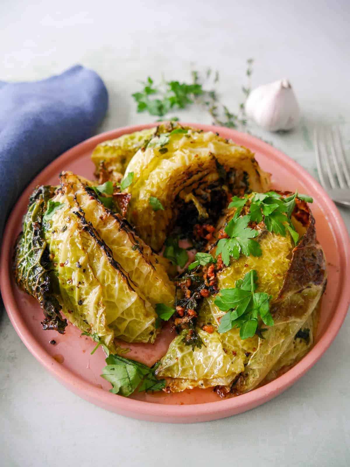 A plate of charred savoy cabbage wedges cooked in a garlic and herb butter.