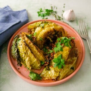 A plate of charred savoy cabbage wedges cooked in a garlic and herb butter.