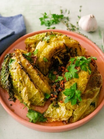 A plate of charred savoy cabbage wedges cooked in a garlic and herb butter.