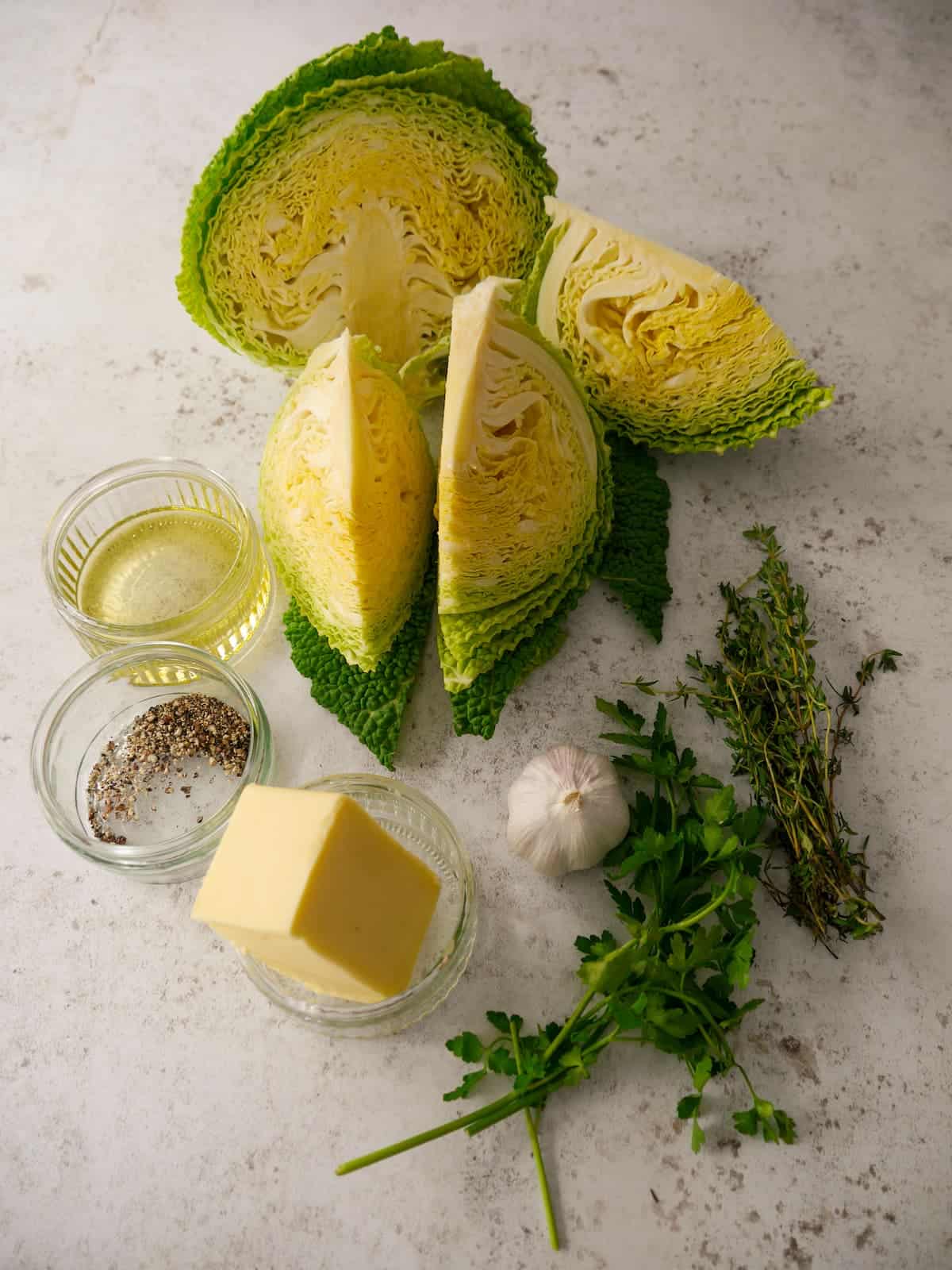 Individual recipe ingredients for making charred cabbage cooked in a garlic and herb butter.