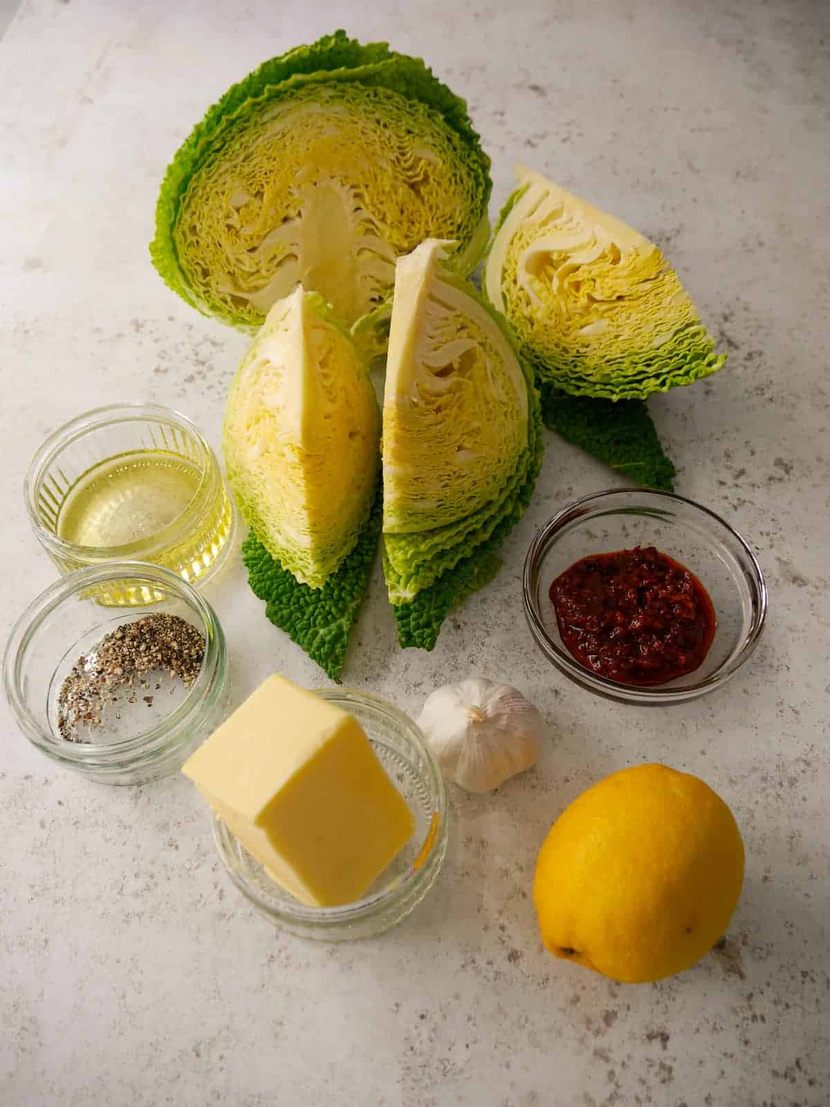 Individual recipe ingredients for making charred cabbage with harissa and lemon butter.