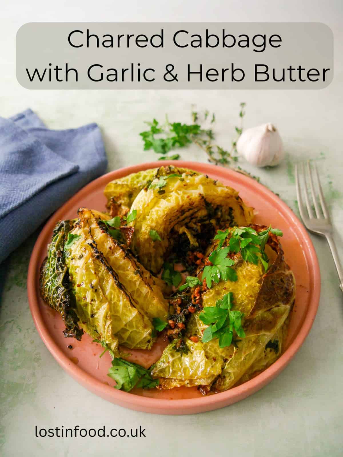 Pinnable image with recipe title and a plate of charred savoy cabbage wedges cooked in a garlic and herb butter.