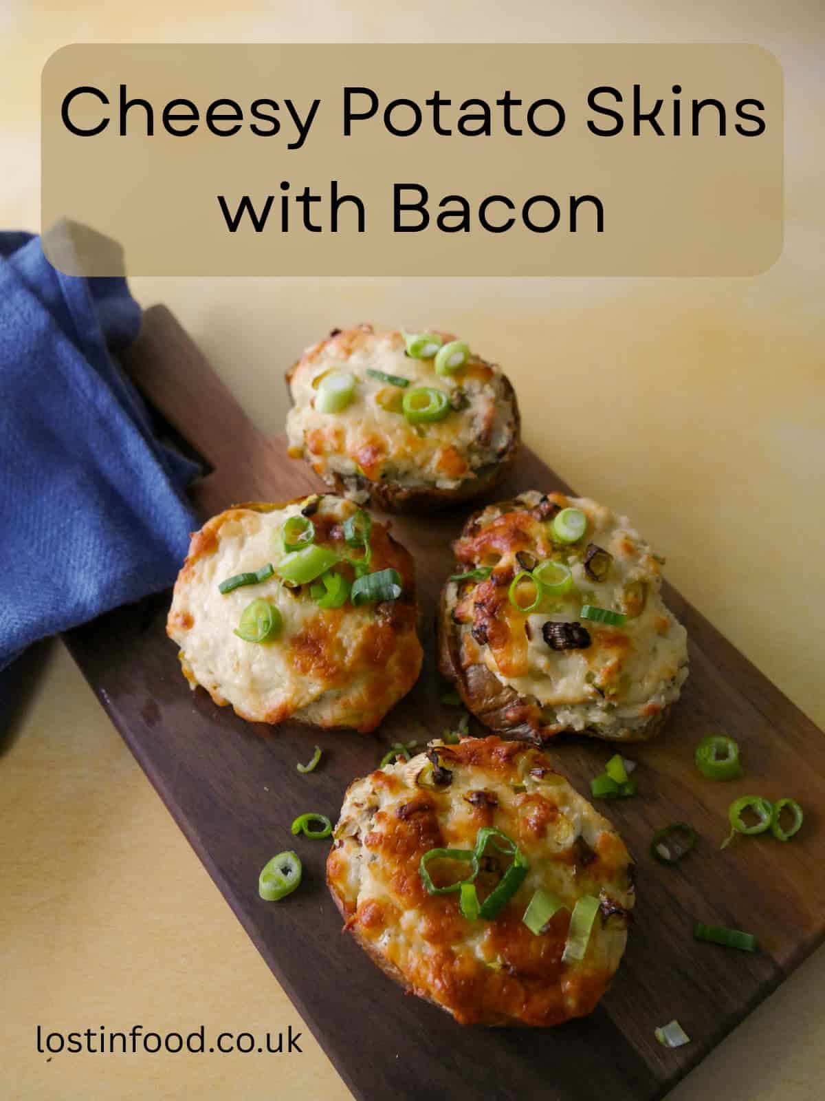 Pinnable image with recipe title and a wooden board topped with cheesy potato skins with a melted cheese and spring onion topping.