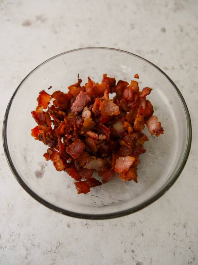 A bowl of cooked crispy bacon pieces.