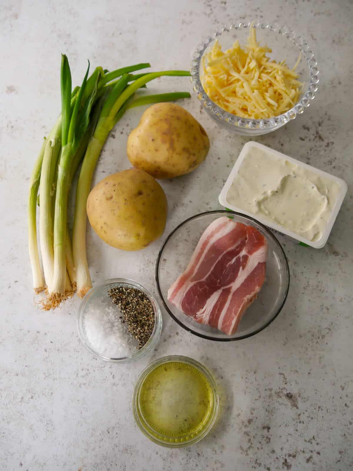Individual recipe ingredients for making cheesy potato skins with bacon and spring onions.