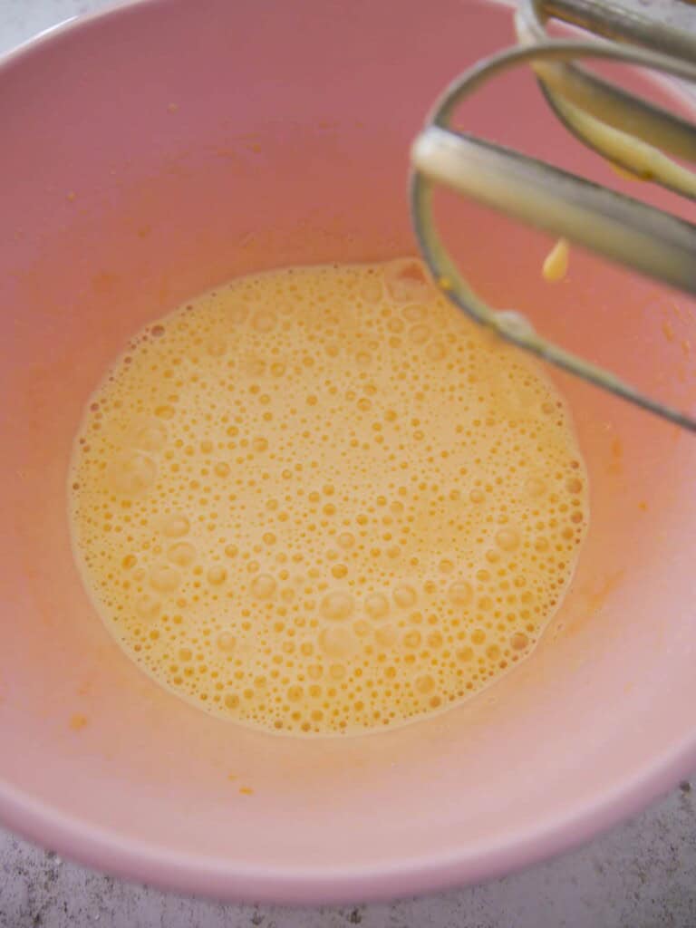 A bowl of frothy whisked eggs and sugar.