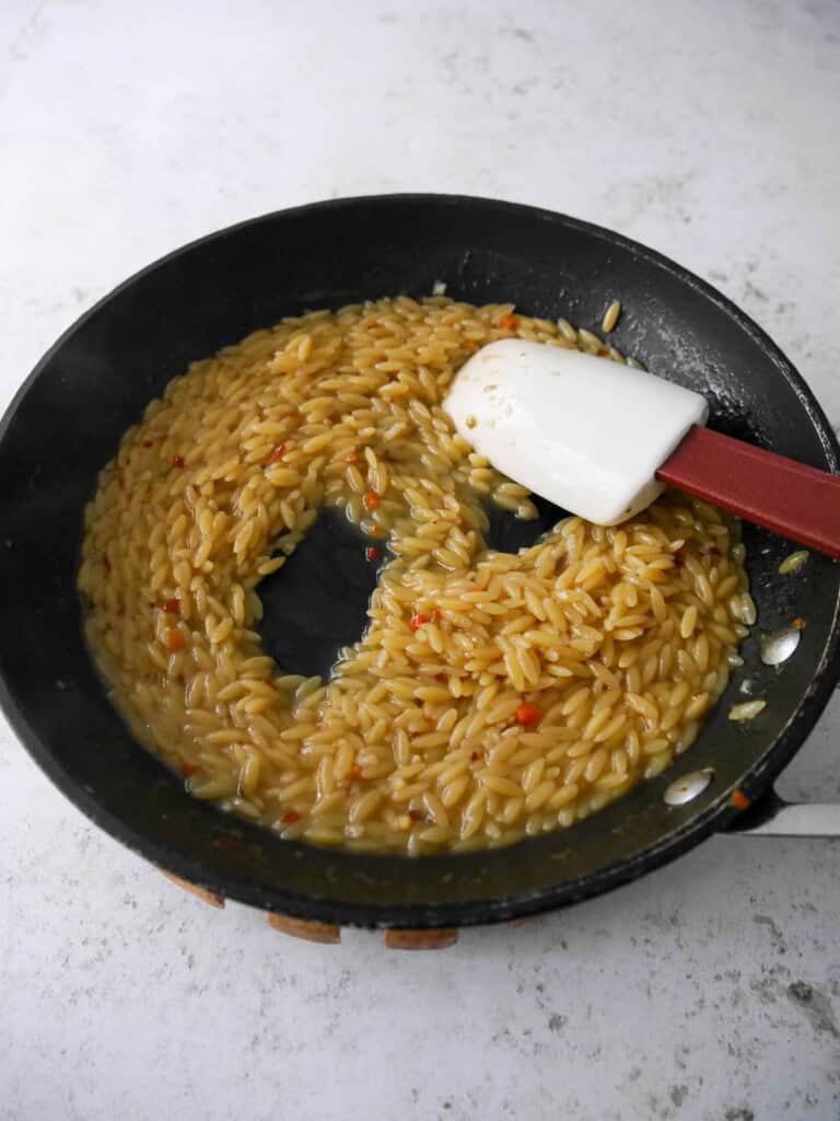A non stick frying pan with cooked orzo pasta.