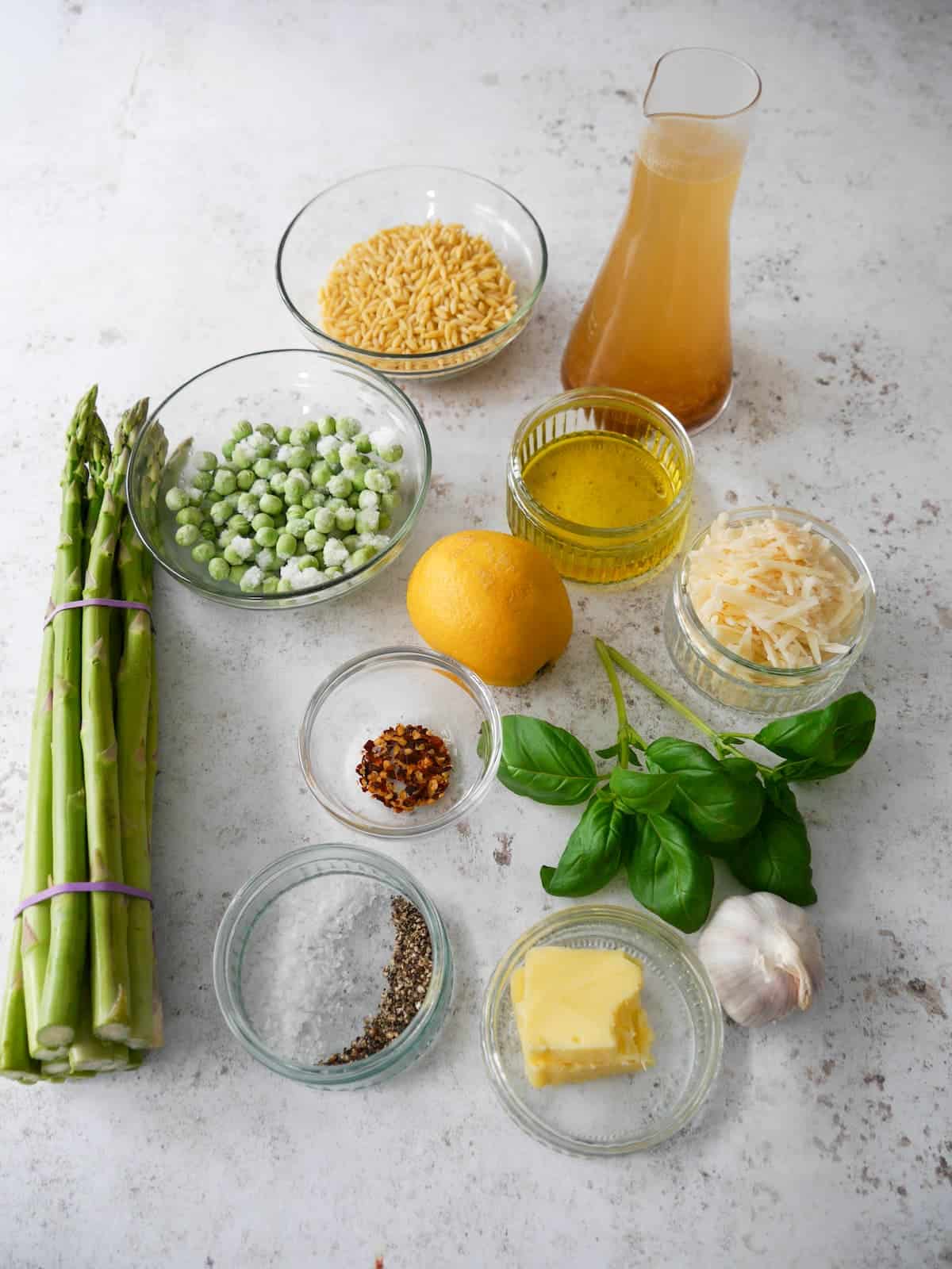Individual recipe ingredients for making lemon orzo pasta with asparagus and peas.