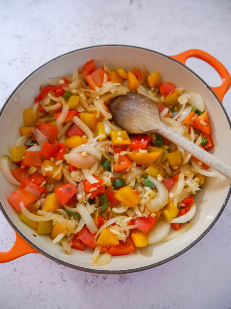 A large skillet of sauteed onions, peppers, chilli, garlic and ginger.