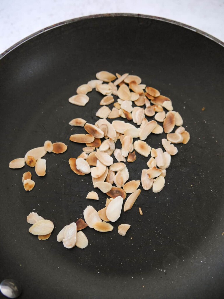 A non stick frying pan with toasted almond flakes.